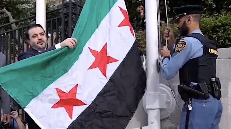 Syria's Foreign Minister Asaad Al-Shibani raises the new Syrian flag. Photo Credit: Syria Foreign Ministry